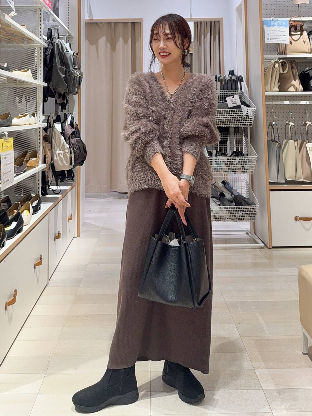 ブラック系のパンプス、ブラック系のボストンバッグ、ブルー系のデニムパンツを着用したレディースの秋コーディネートの2枚目の写真