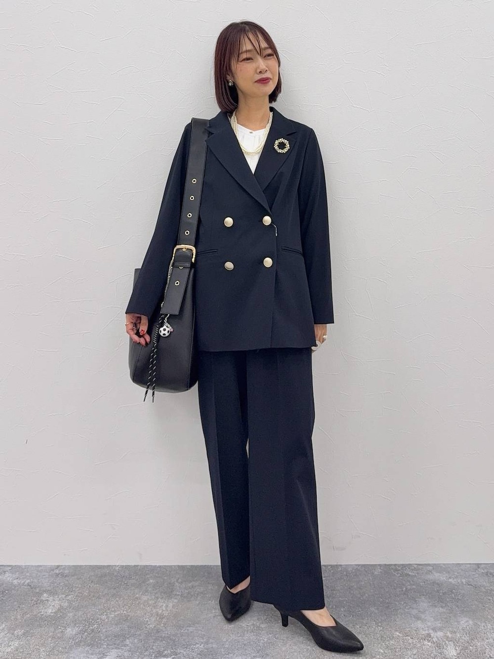 ブラック系のスニーカー、ブラック系のトートバッグ、ブルー系のテーラードジャケットを着用したレディースの冬コーディネートの3枚目の写真