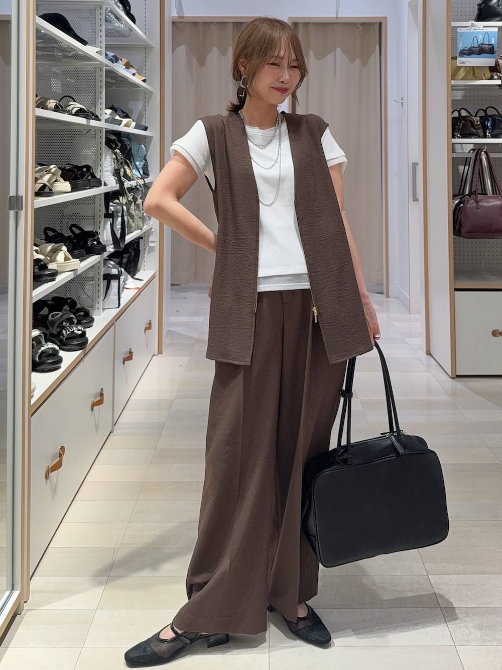 レッド系のボストンバッグ、ブルー系のデニムパンツ、ブラウン系のベストを着用したレディースの夏コーディネートの2枚目の写真