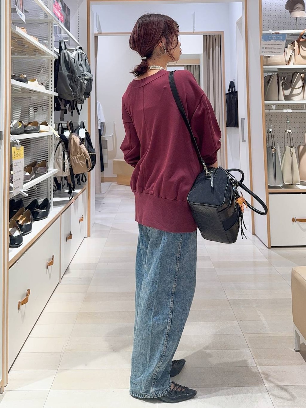 ホワイト系のキャミソール、ブルー系のデニムパンツ、ブラック系のボストンバッグを着用したレディースの秋コーディネートの9枚目の写真