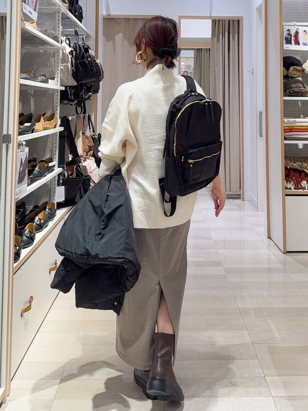 ブラック系のダウンジャケット/コート、ブラウン系のスカート、ホワイト系のニット/セーターを着用したレディースの冬コーディネートの6枚目の写真