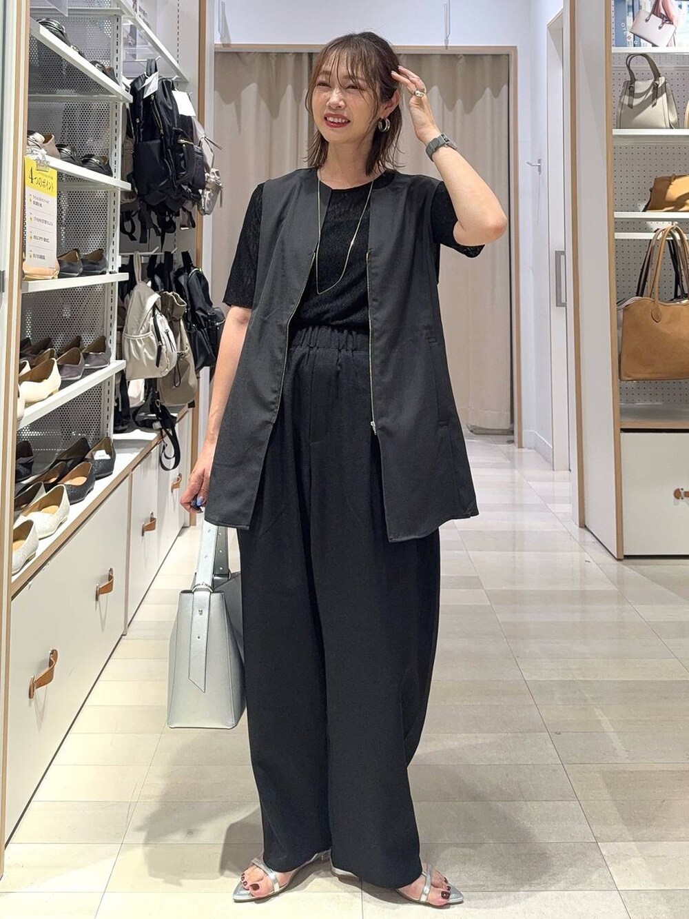 シルバー系のショルダーバッグ、ブラック系のTシャツ/カットソー、シルバー系のサンダルを着用したレディースの夏コーディネートの2枚目の写真