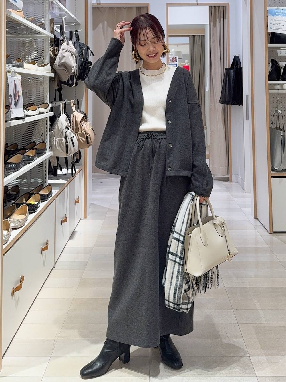 ホワイト系のショルダーバッグ、ブラック系のブーツ、ブラウン系のバレッタ/ヘアクリップを着用したレディースの秋コーディネートの2枚目の写真