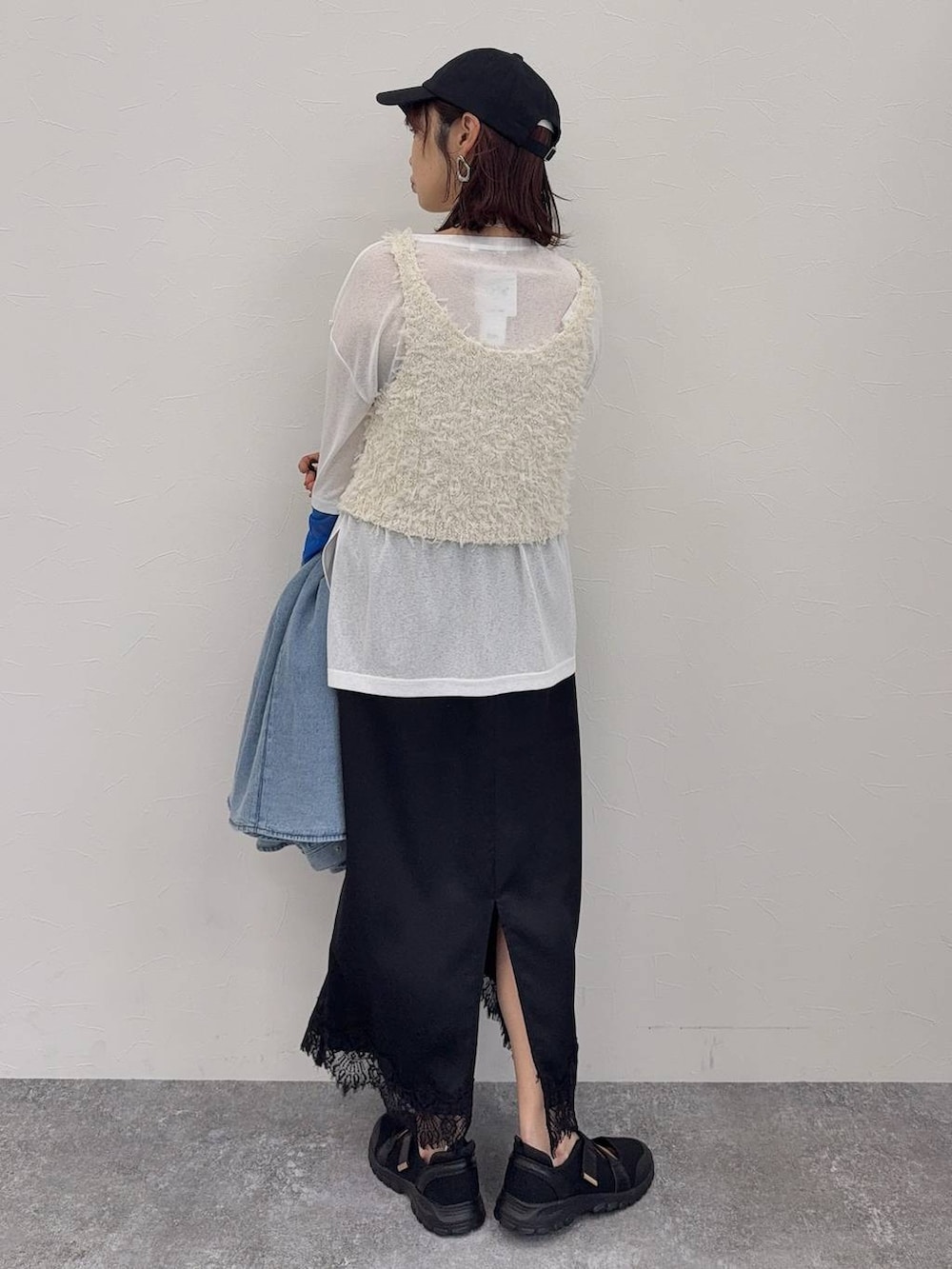 ブラック系のスニーカー、ホワイト系のベスト、シルバー系のネックレスを着用したレディースの春コーディネートの7枚目の写真