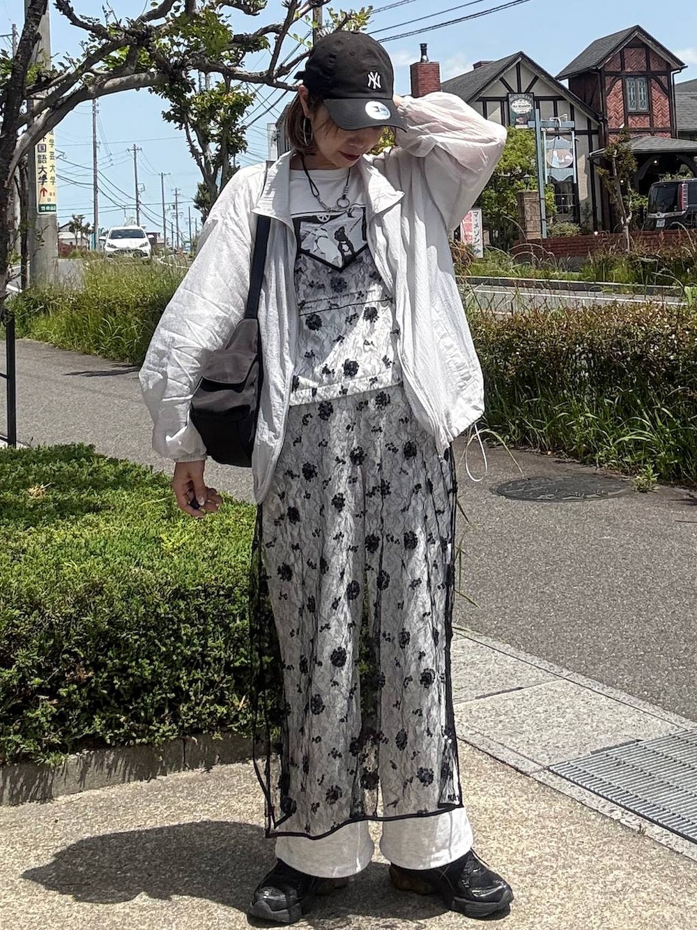 ブラック系のショルダーバッグ、ホワイト系のTシャツ/カットソー、ブラック系のワンピースを着用したレディースの春コーディネートの2枚目の写真