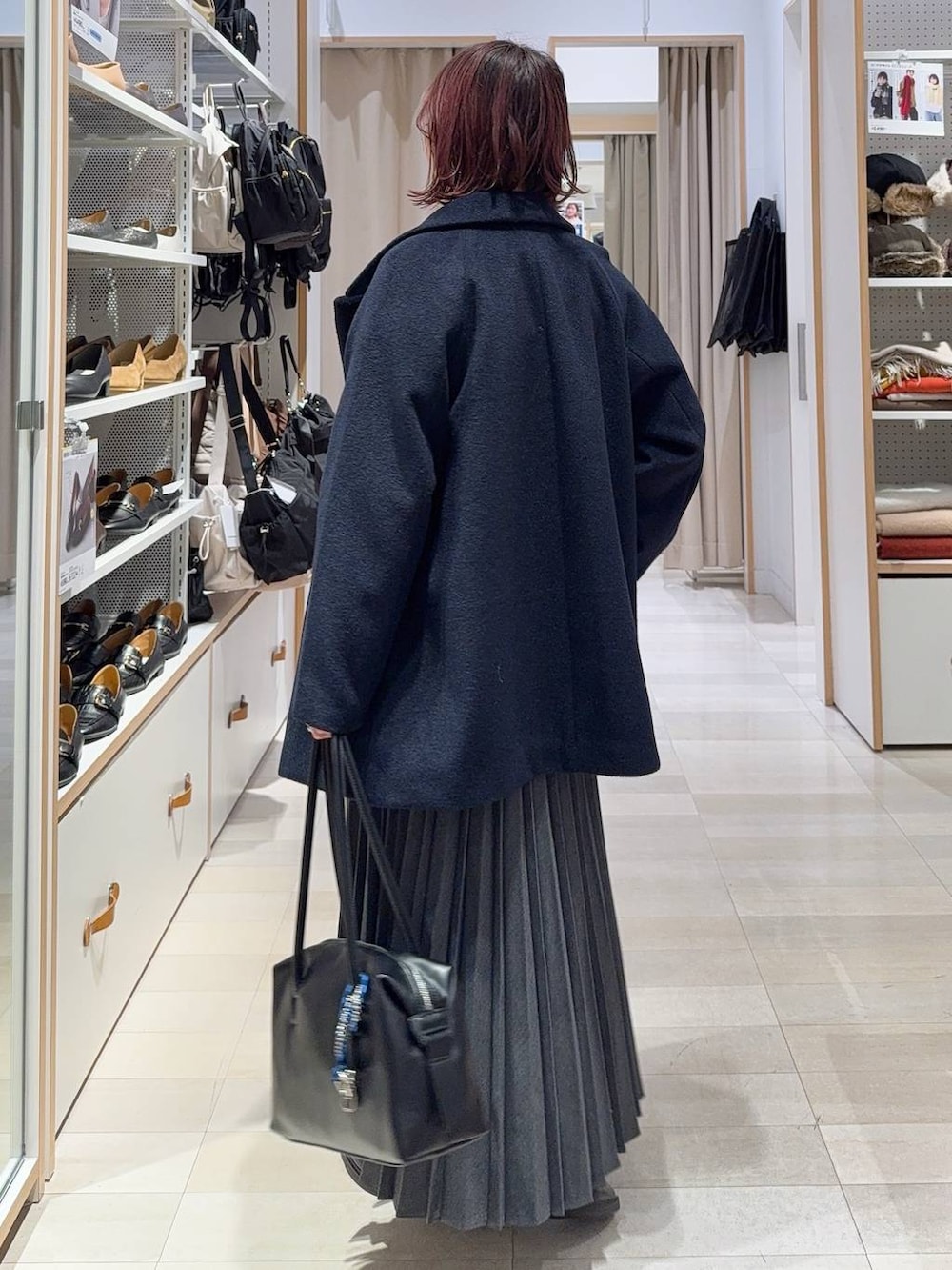 ブラック系のボストンバッグ、ブルー系のチェスターコート、イエロー系のシャツ/ブラウスを着用したレディースの冬コーディネートの5枚目の写真