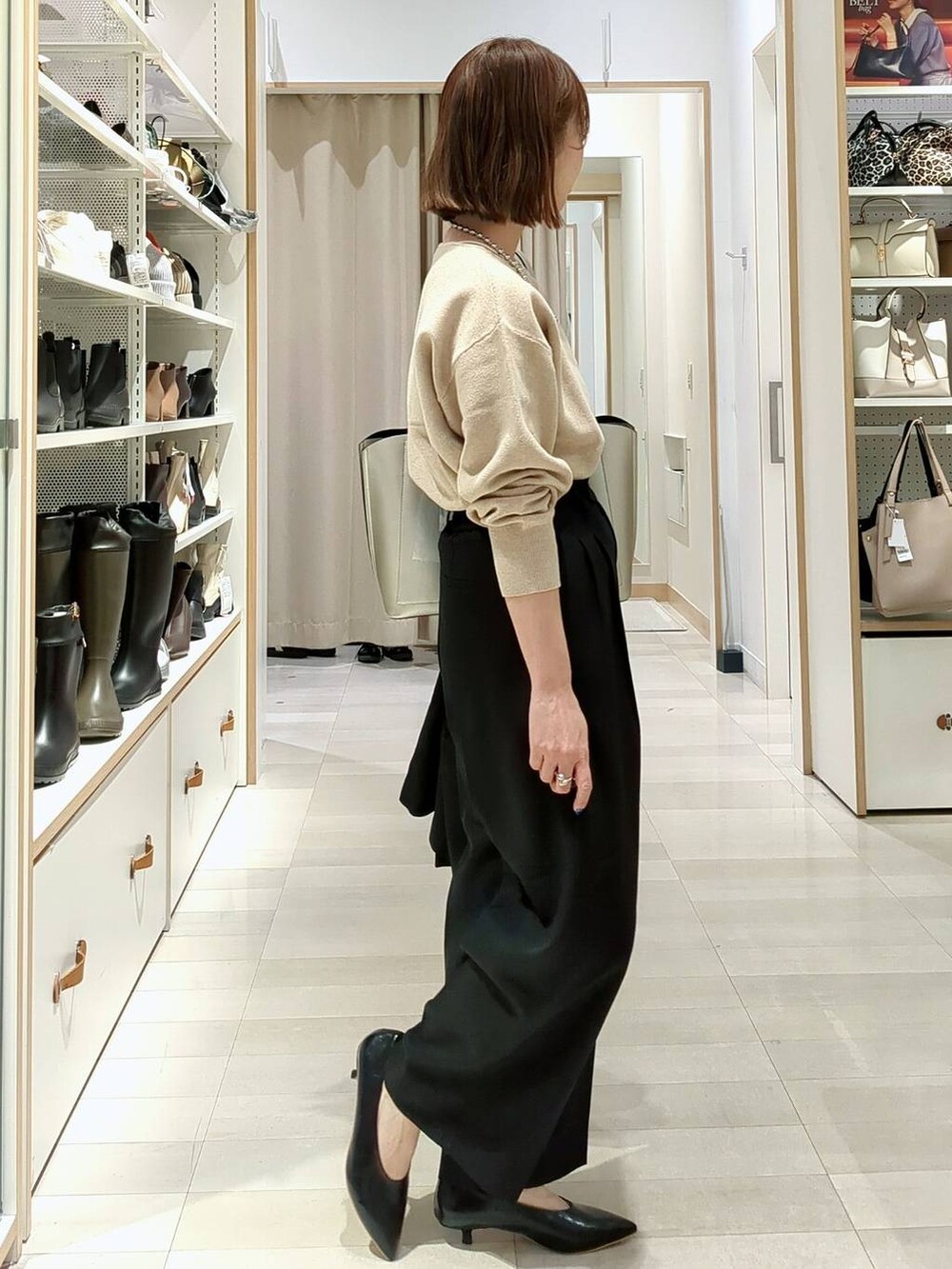 シルバー系のトートバッグ、ベージュ系のニット/セーター、ブラック系のその他パンツを着用したレディースの春コーディネートの7枚目の写真