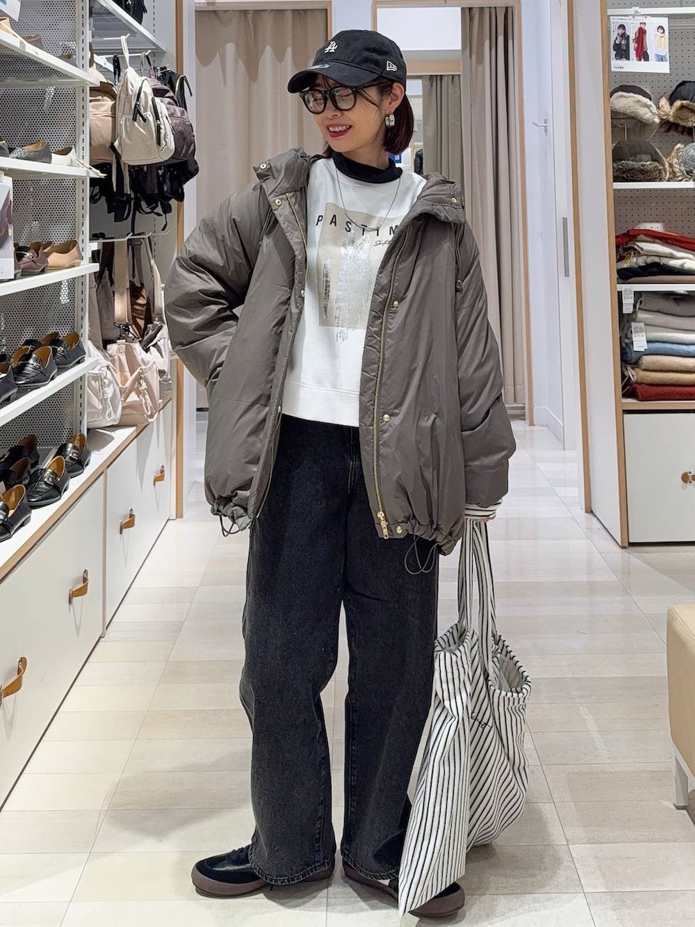 ブラック系のスニーカー、ブラウン系のダウンジャケット/コート、ブラック系のデニムパンツを着用したレディースの秋コーディネートの2枚目の写真