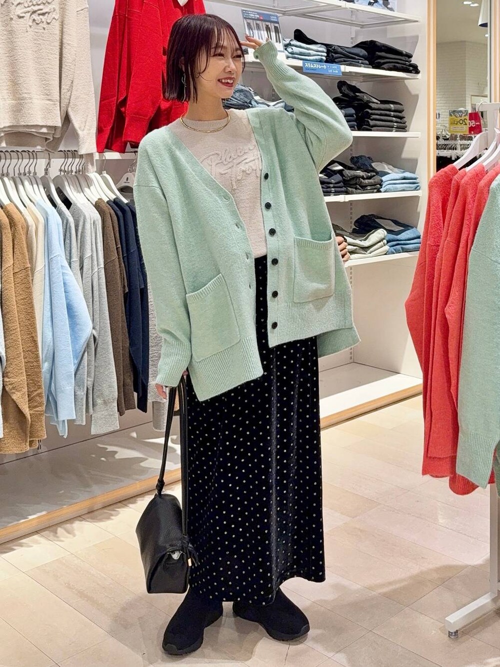 グレー系のバレエシューズ、シルバー系のハンドバッグ、ブルー系のデニムパンツを着用したレディースの秋コーディネートの2枚目の写真