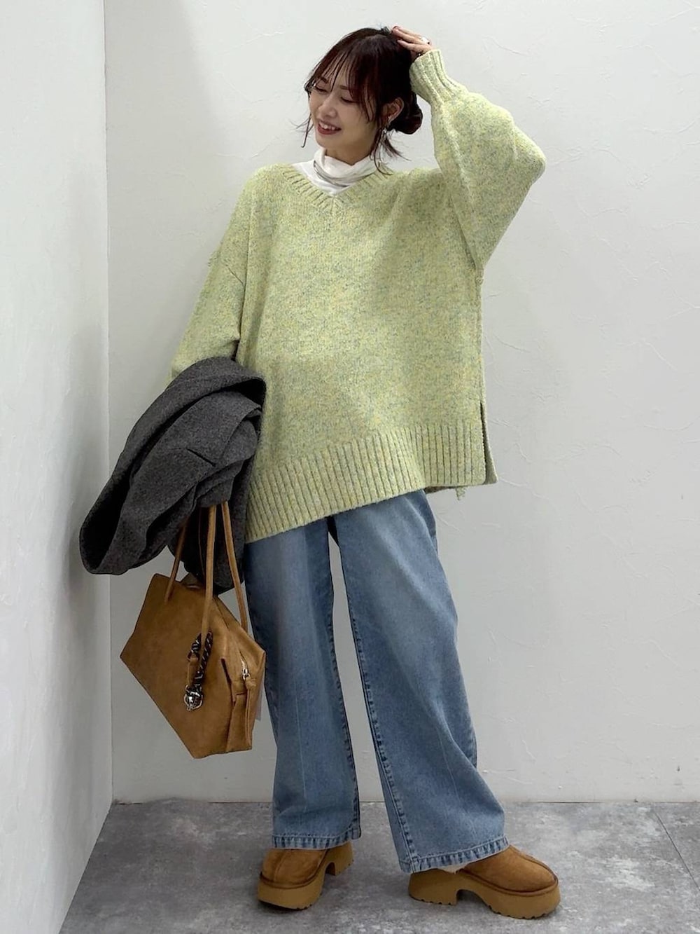 ベージュ系のボストンバッグ、グレー系のチェスターコート、イエロー系のブーツを着用したレディースの冬コーディネートの3枚目の写真