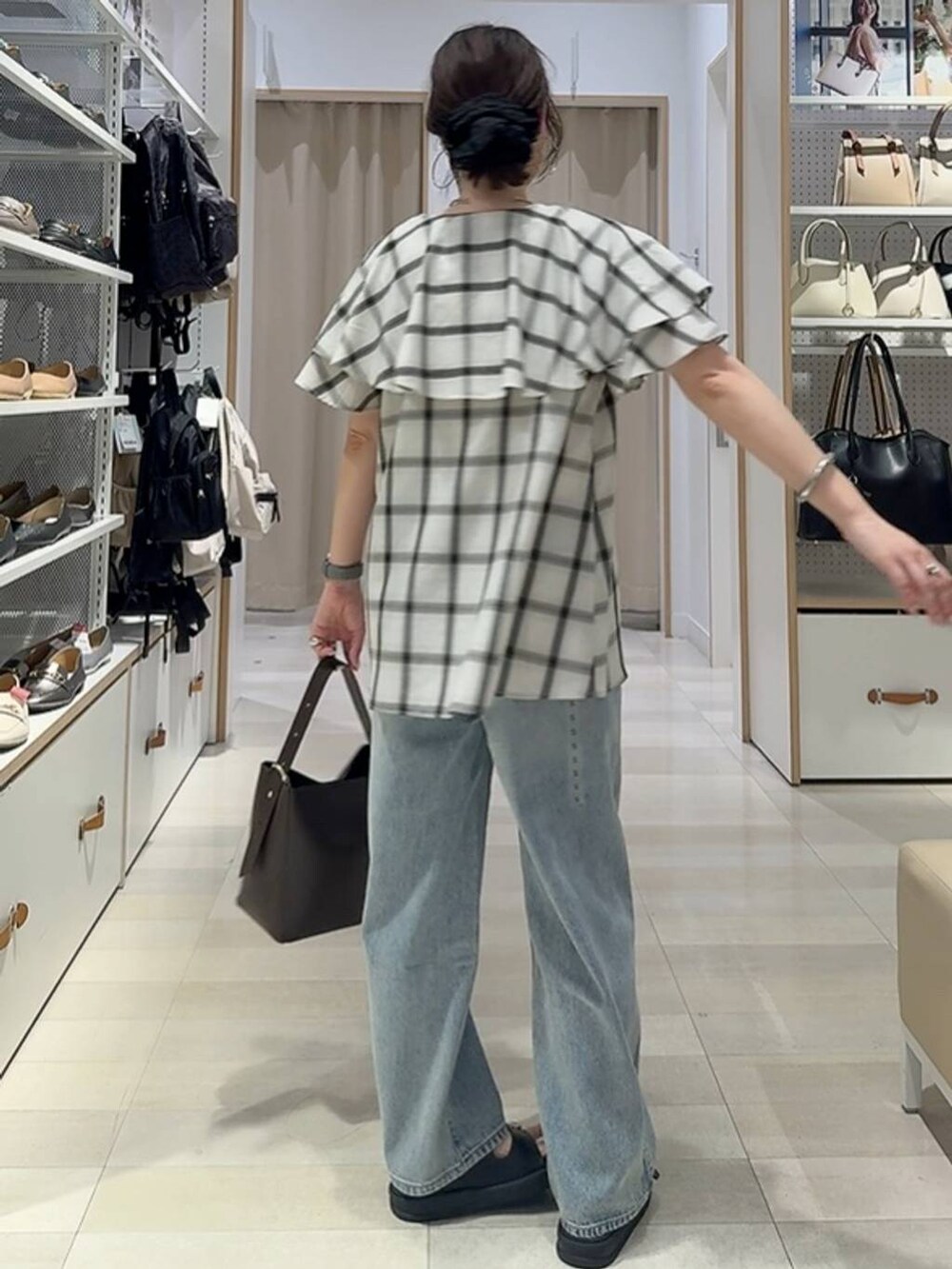 ブルー系のデニムパンツ、ブラウン系のショルダーバッグ、ホワイト系のシャツ/ブラウスを着用したレディースの夏コーディネートの3枚目の写真