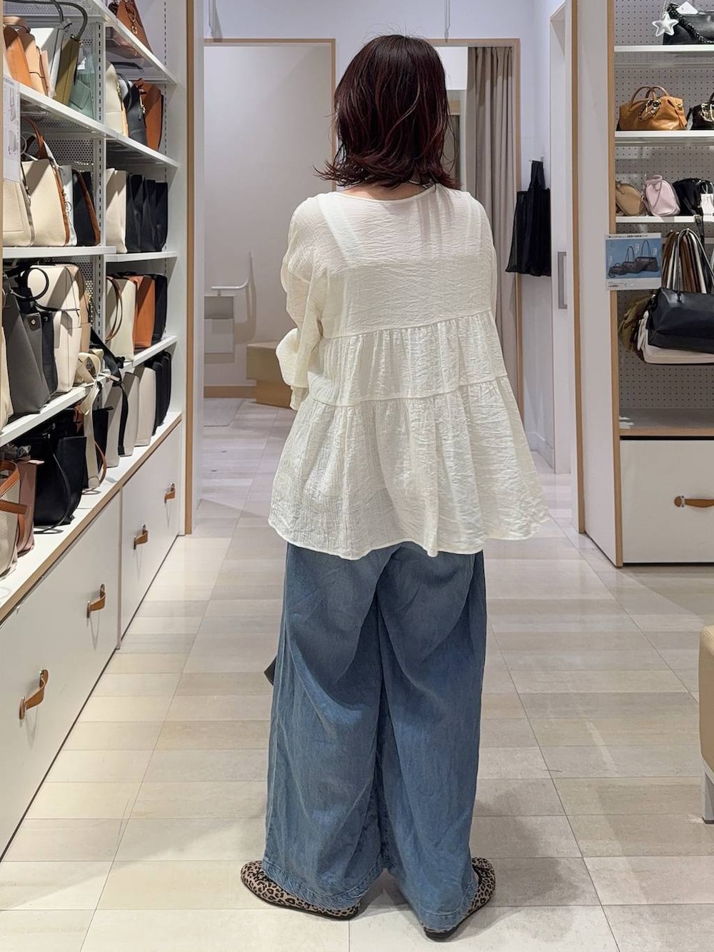 ブラウン系のベスト、ブルー系のデニムパンツ、その他のネックレスを着用したレディースの春コーディネートの9枚目の写真