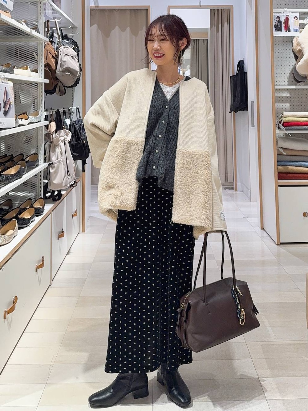 ブラウン系のボストンバッグ、ホワイト系のTシャツ/カットソー、ブラック系のスカートを着用したレディースの秋コーディネートの2枚目の写真