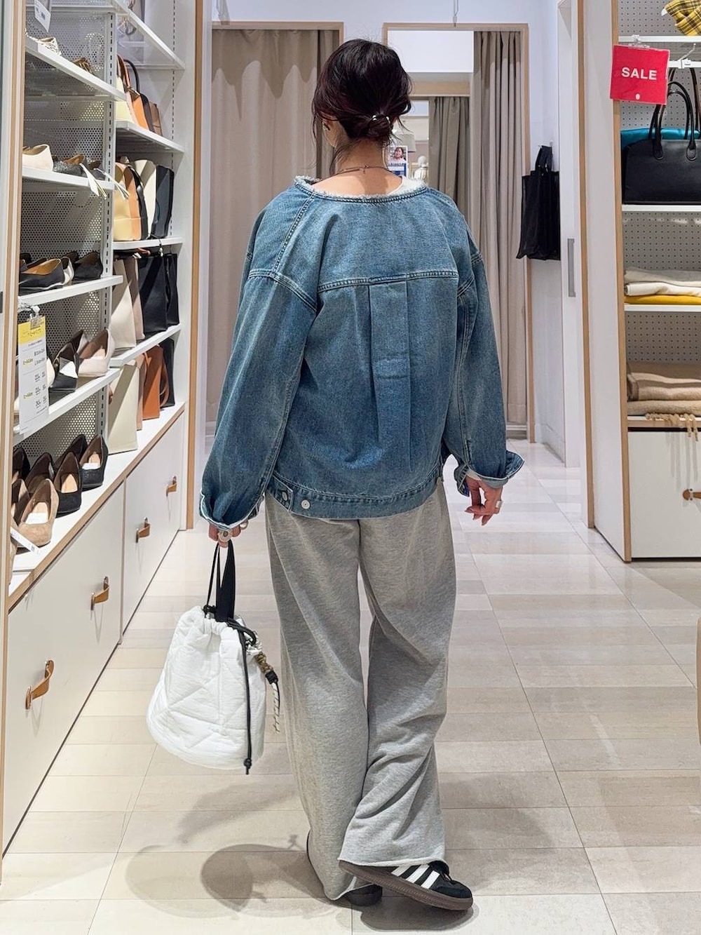 ブラック系のキャミソール、ホワイト系のハンドバッグ、ブルー系のデニムジャケットを着用したレディースの冬コーディネートの4枚目の写真