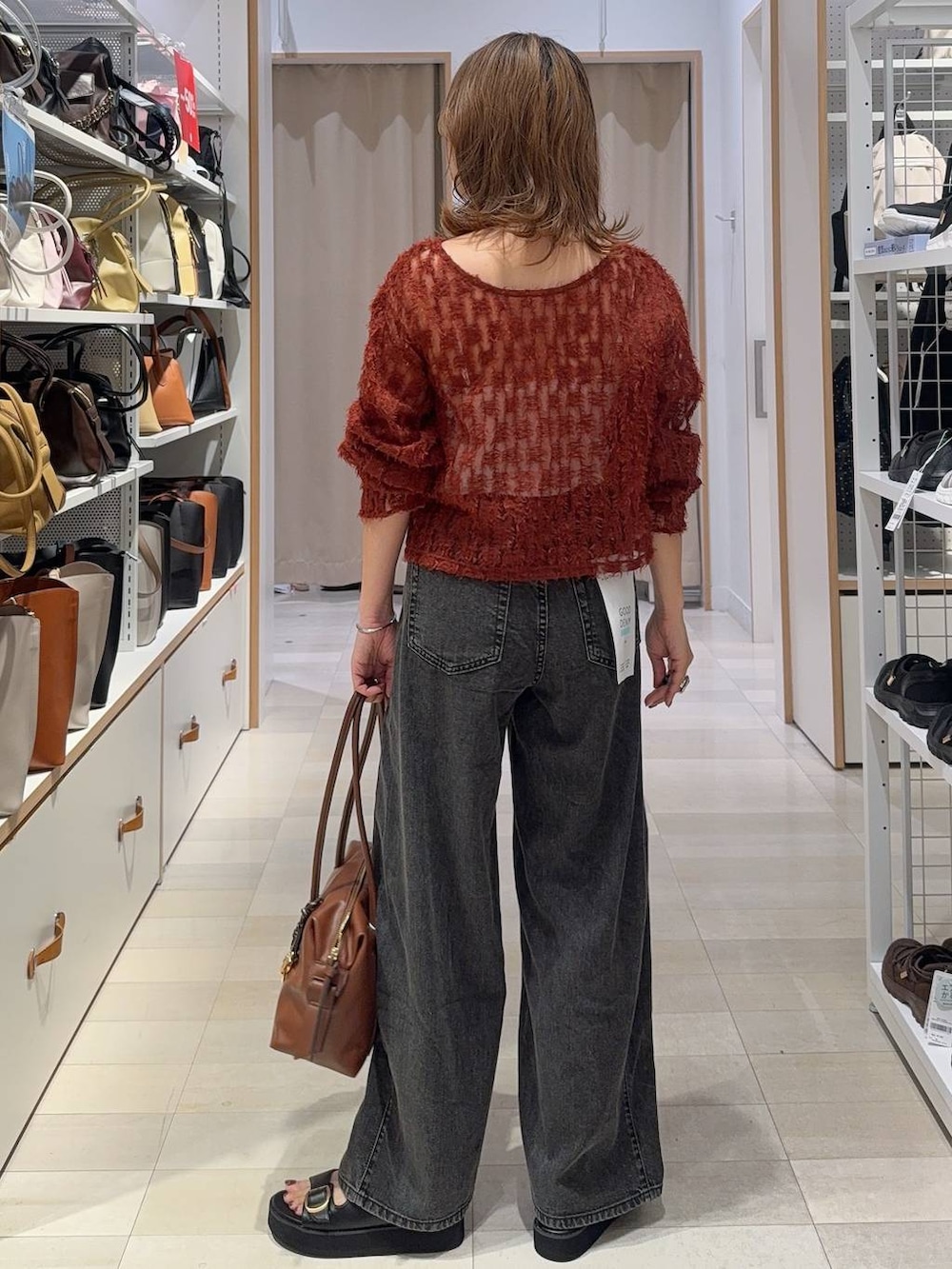 レッド系のカーディガン/ボレロ、ブラウン系のボストンバッグ、ブラック系のデニムパンツを着用したレディースの夏コーディネートの4枚目の写真