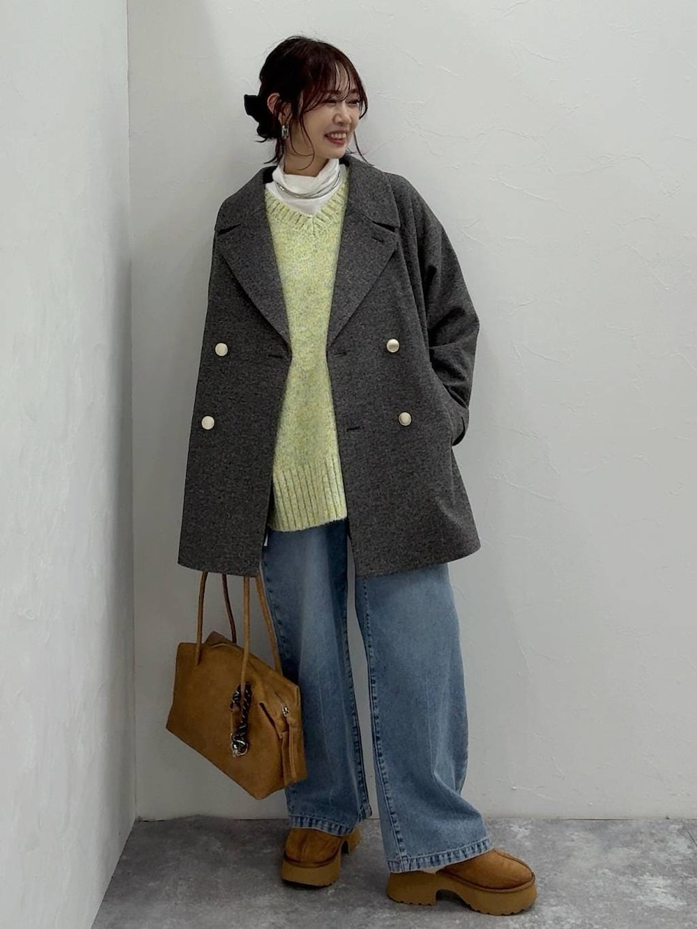 ベージュ系のボストンバッグ、グレー系のチェスターコート、イエロー系のブーツを着用したレディースの冬コーディネートの2枚目の写真