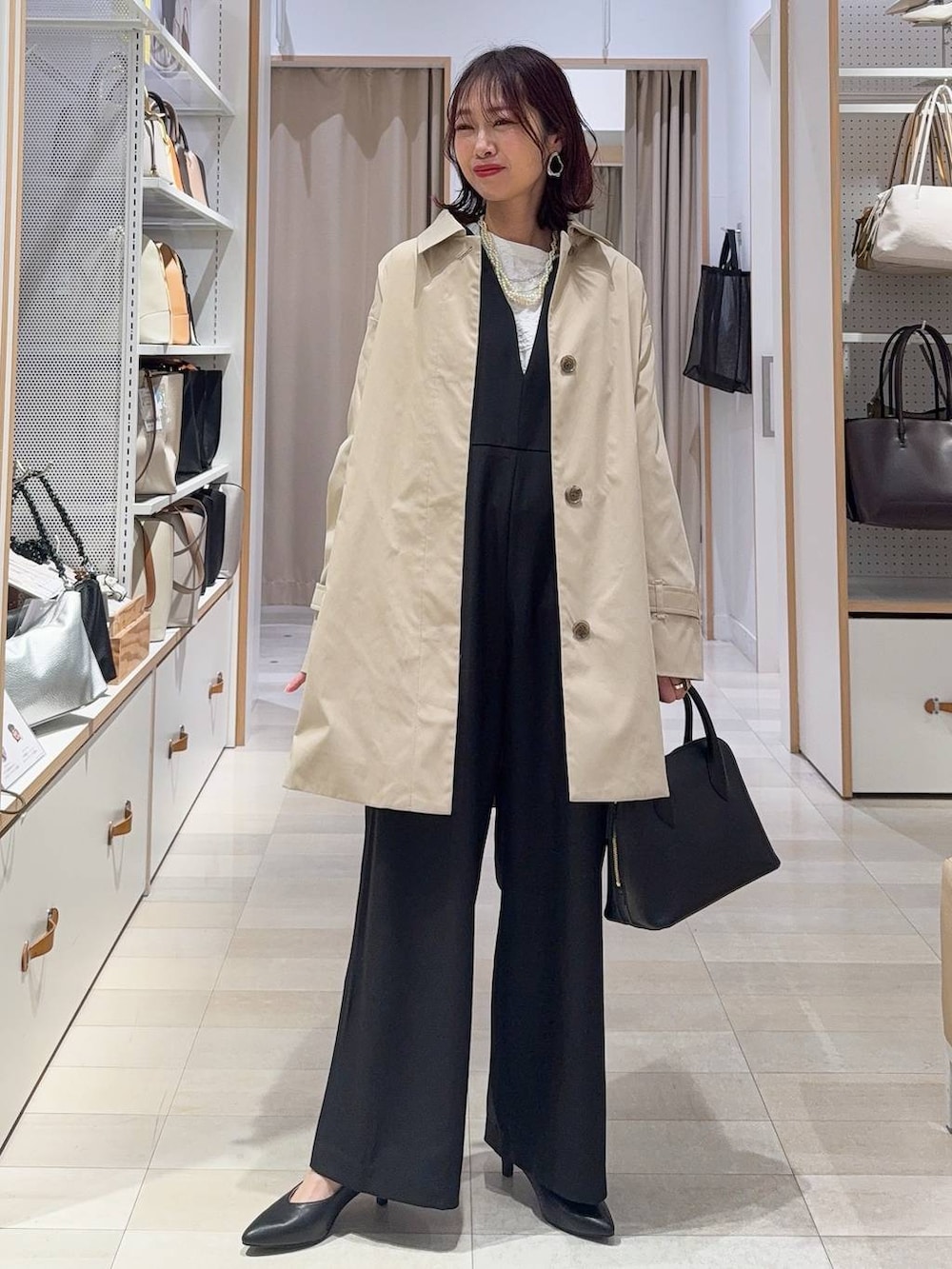 ブラック系のショルダーバッグ、ブラック系のパンプス、ベージュ系のステンカラーコートを着用したレディースの冬コーディネートの2枚目の写真