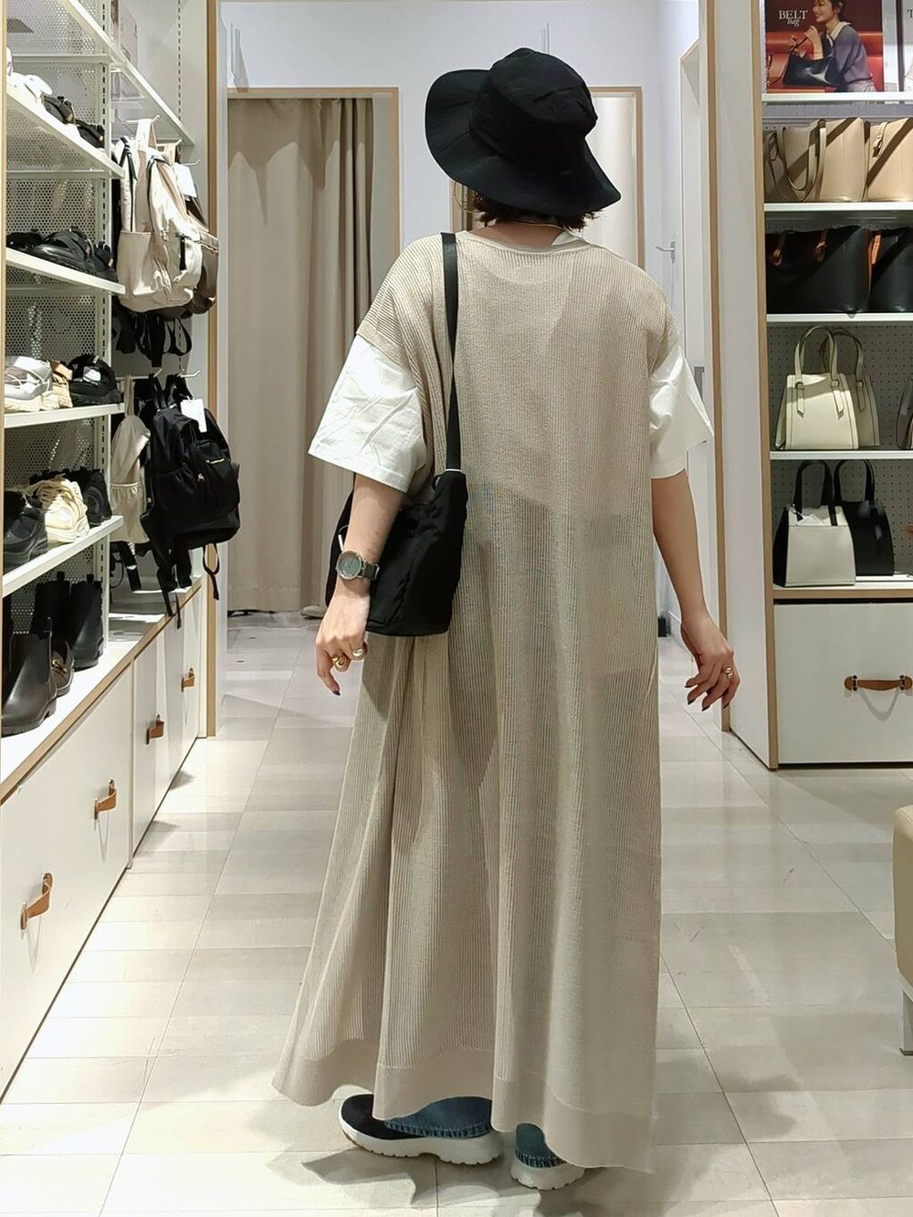 ブラック系のスニーカー、ブルー系のデニムパンツ、ベージュ系のワンピースを着用したレディースの春コーディネートの6枚目の写真