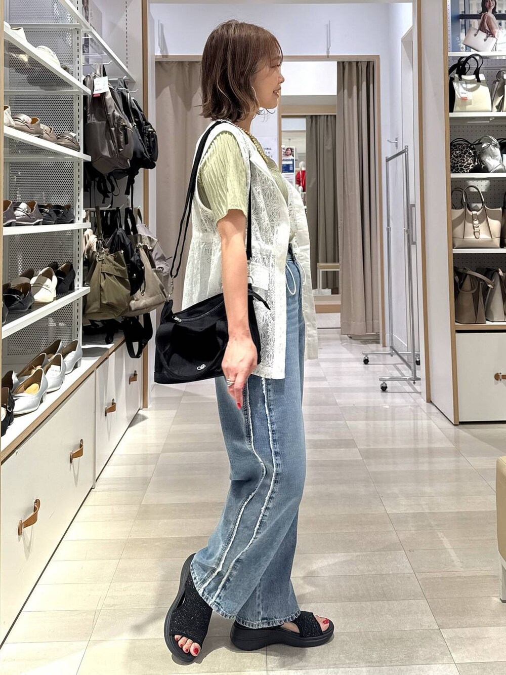 ブルー系のデニムパンツ、ブラック系のトートバッグ、グリーン系のTシャツ/カットソーを着用したレディースの春コーディネートの4枚目の写真