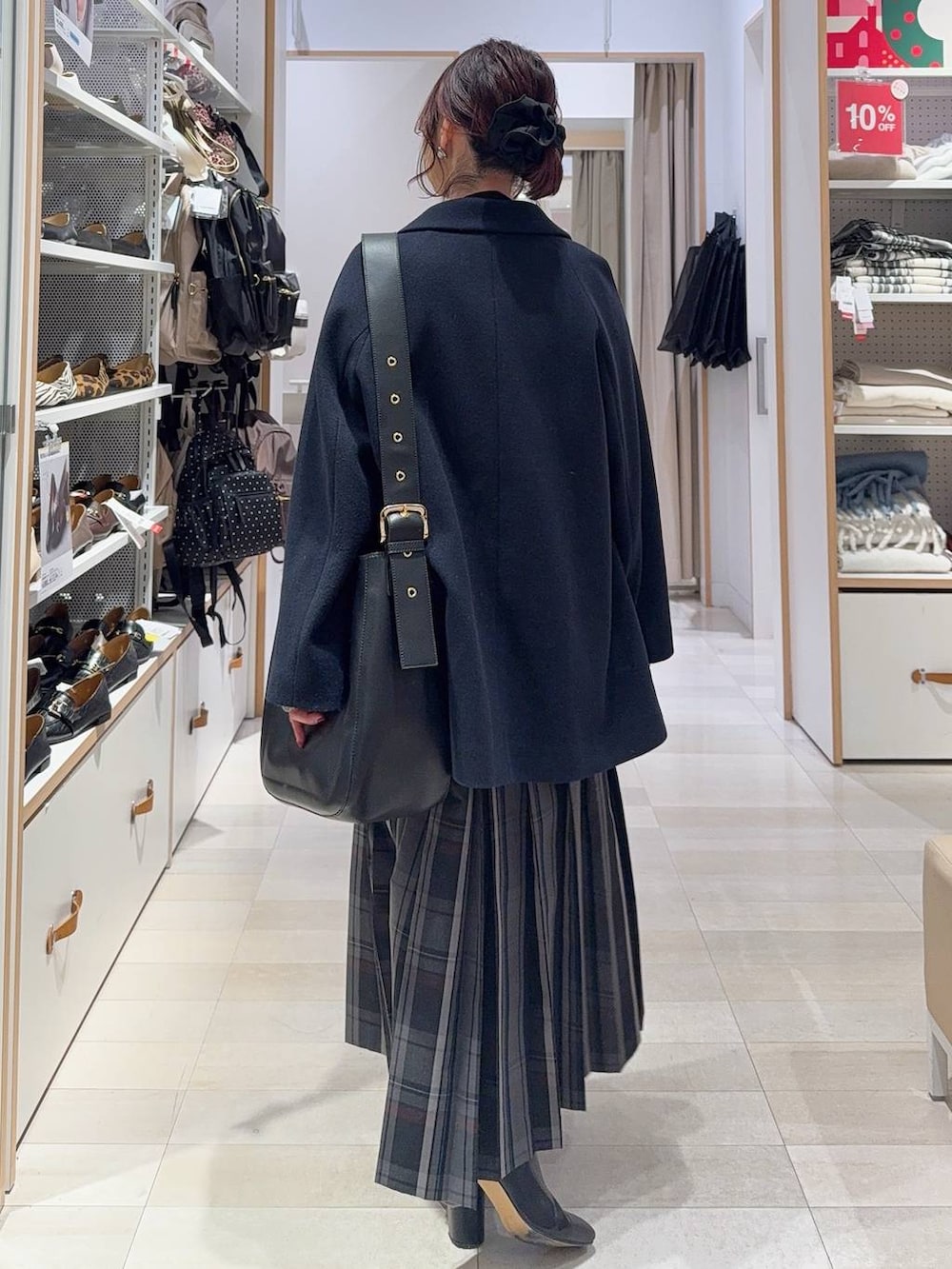 ブラック系のショルダーバッグ、ブルー系のチェスターコート、グレー系のスカートを着用したレディースの冬コーディネートの9枚目の写真