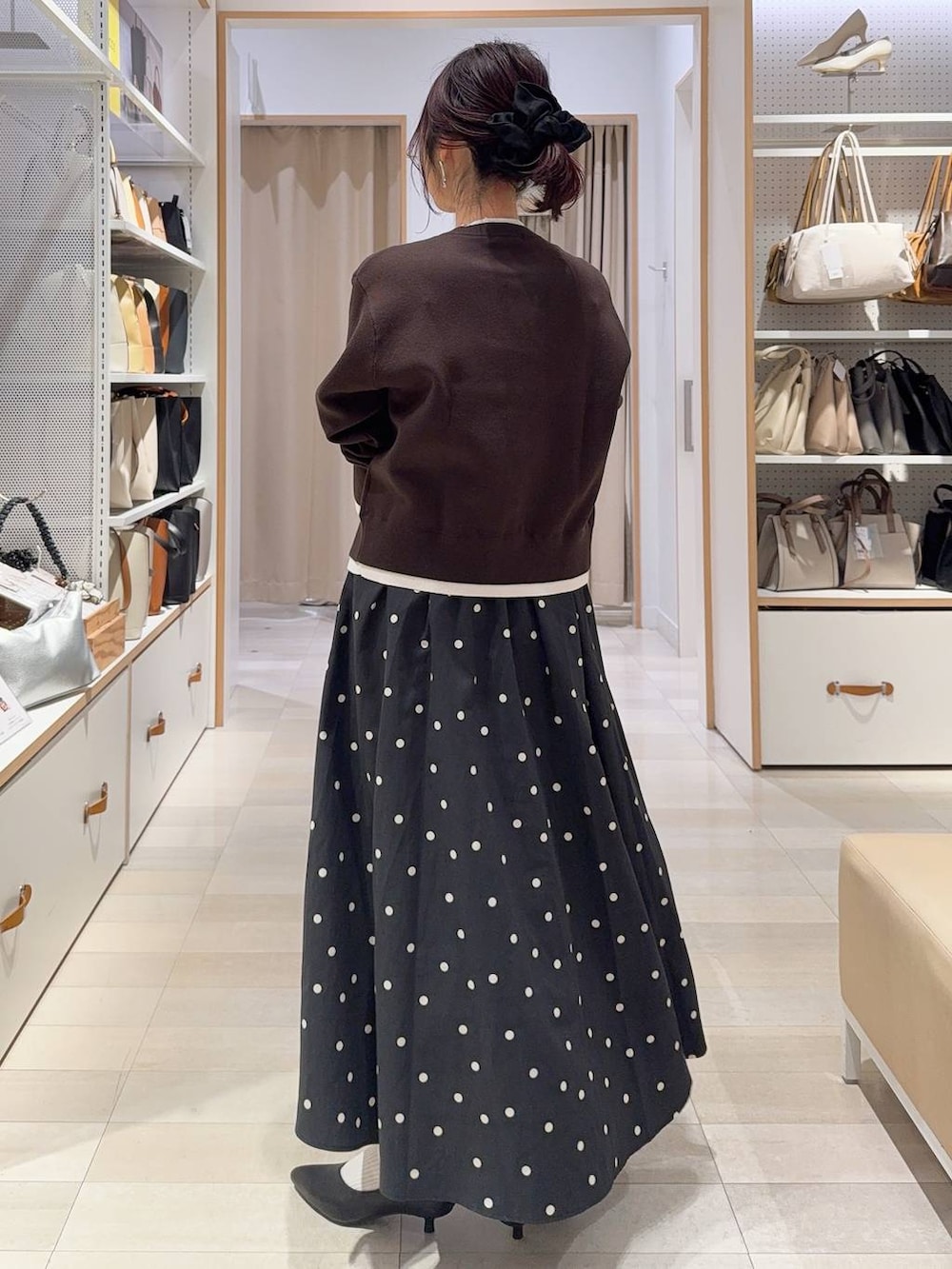 ブラック系のハンドバッグ、ブラウン系のカーディガン/ボレロ、ブラック系のパンプスを着用したレディースの冬コーディネートの8枚目の写真