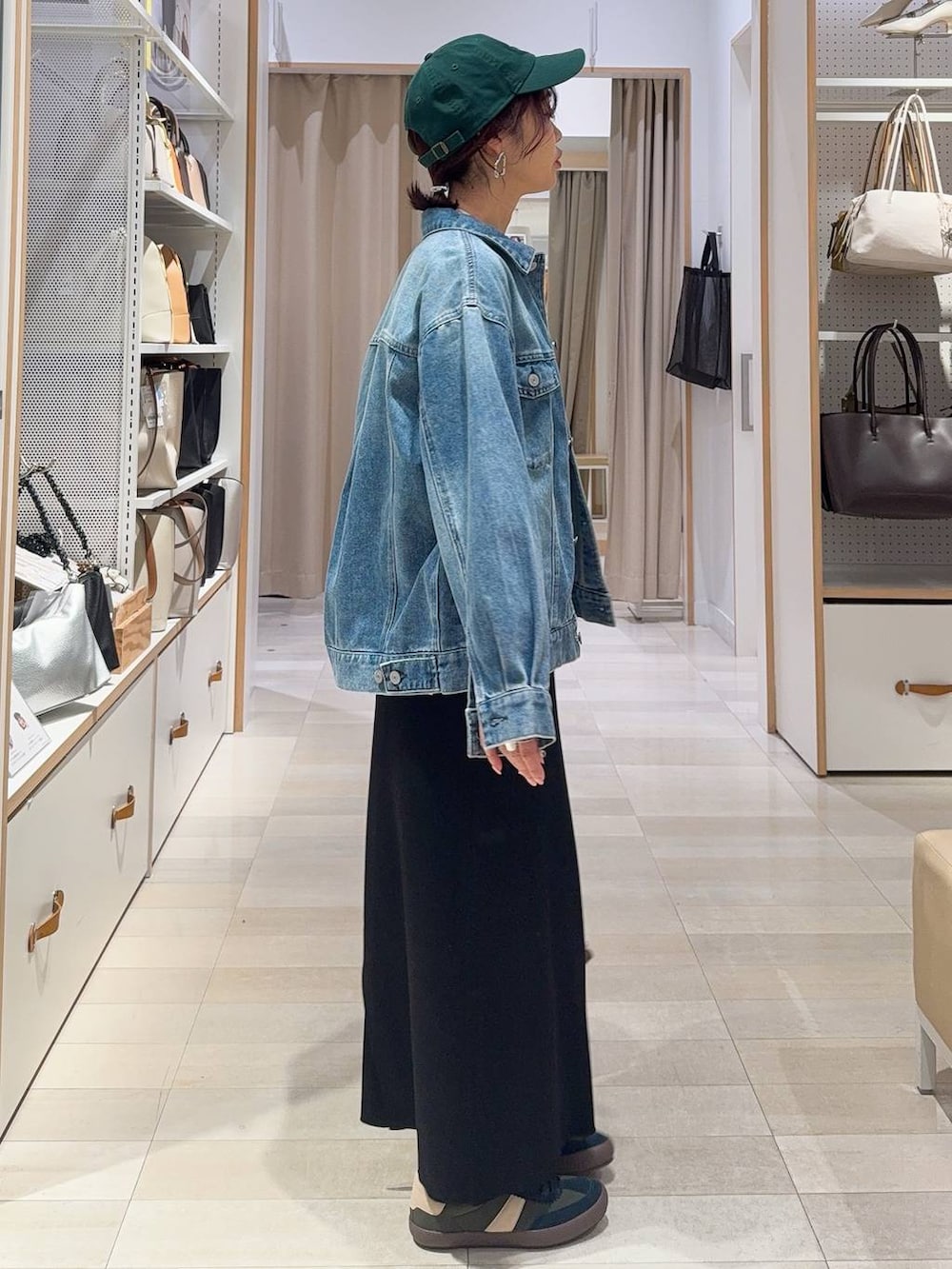 グリーン系のスニーカー、ブルー系のデニムジャケット、ブラック系のスカートを着用したレディースの冬コーディネートの5枚目の写真