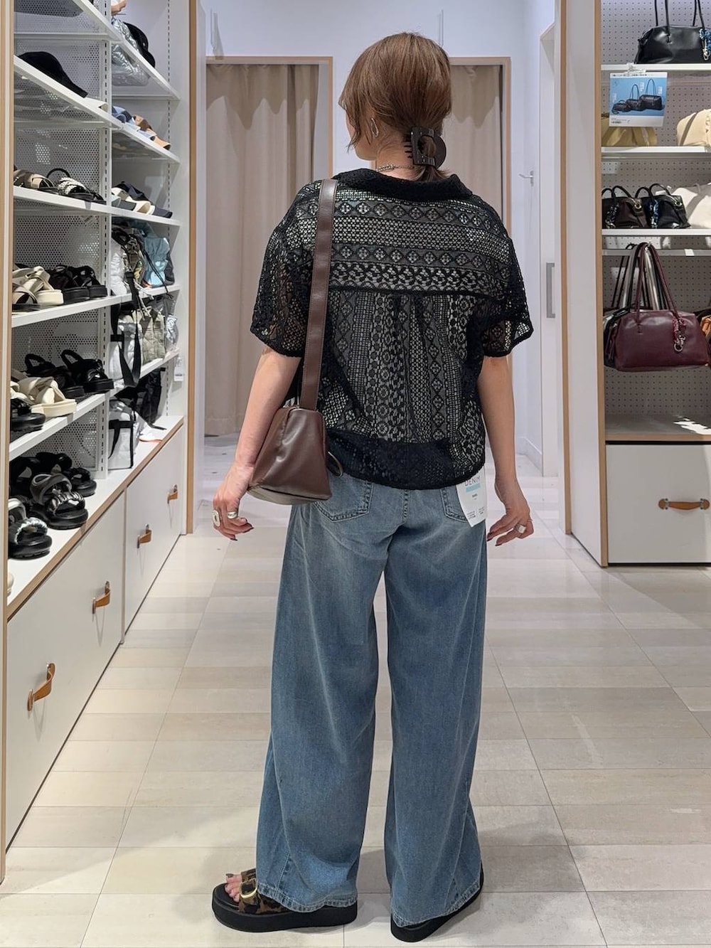 ブルー系のデニムパンツ、ブラウン系のショルダーバッグ、その他のサンダルを着用したレディースの夏コーディネートの5枚目の写真