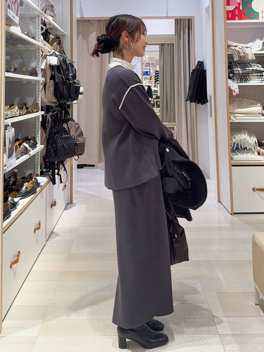 ブラウン系のボストンバッグ、ブラック系のチェスターコート、ホワイト系のTシャツ/カットソーを着用したレディースの冬コーディネートの8枚目の写真