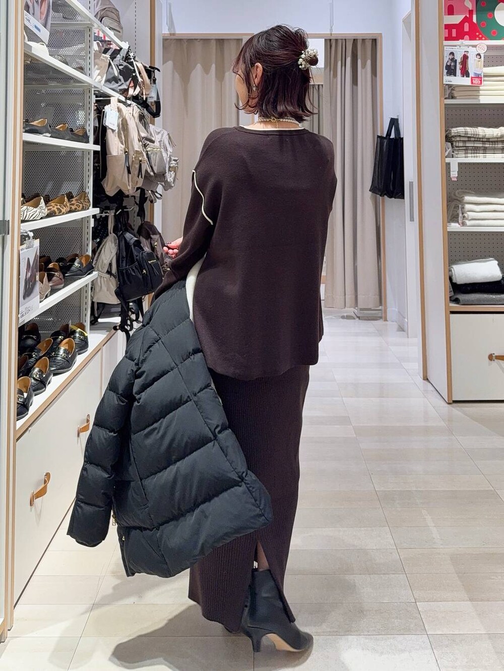 ブラック系のダウンジャケット/コート、ブラウン系のワンピース、ブラック系のブーツを着用したレディースの冬コーディネートの8枚目の写真