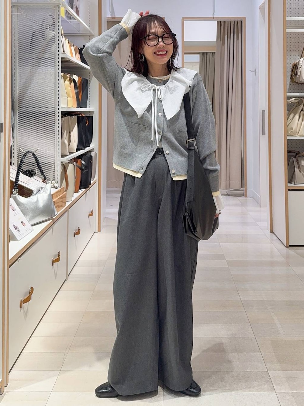 ブラウン系のボストンバッグ、ブルー系のデニムパンツ、レッド系のカーディガン/ボレロを着用したレディースの春コーディネートの5枚目の写真