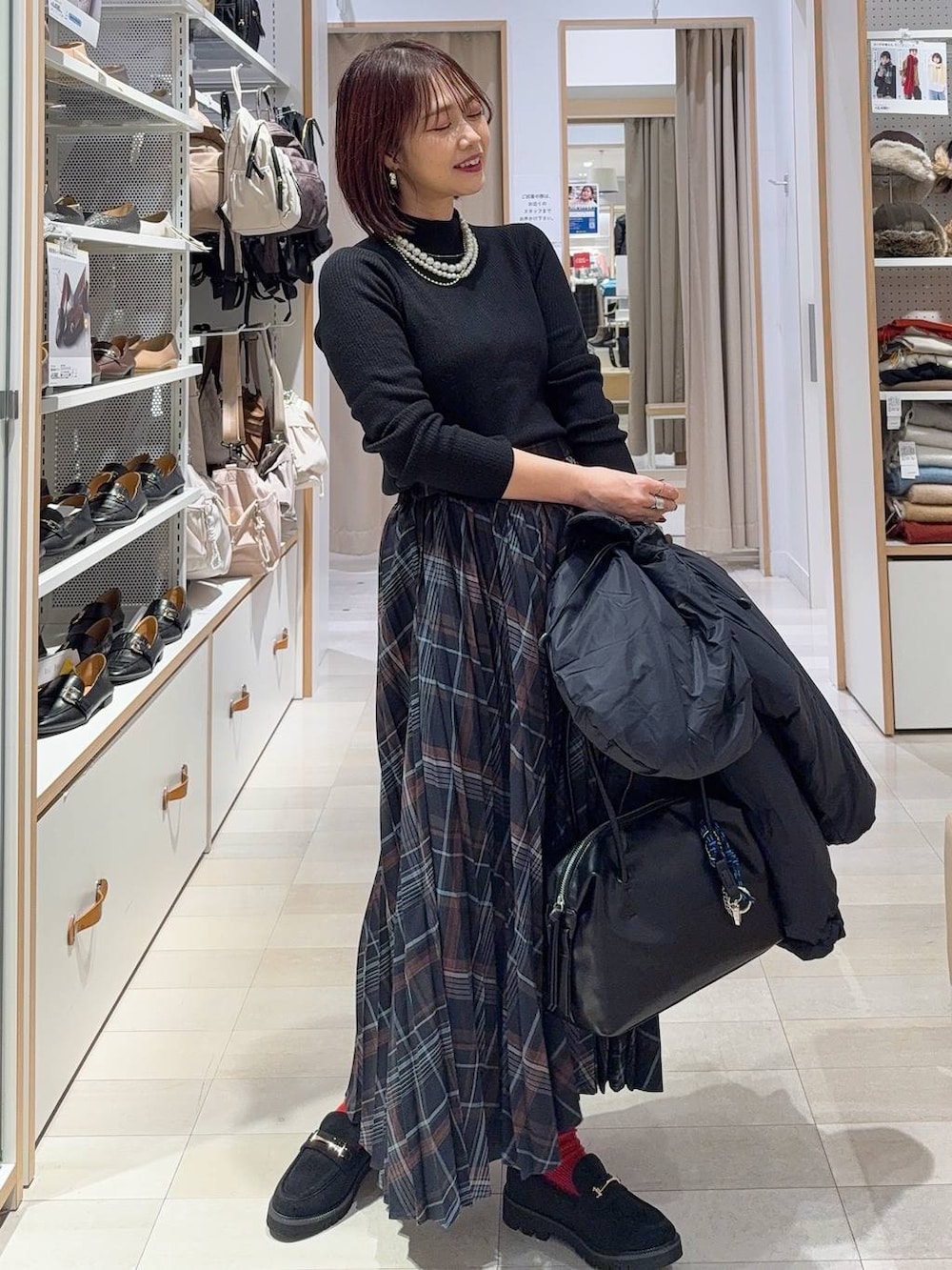 ブルー系のダウンジャケット/コート、ブラウン系のボストンバッグ、ブラック系のニット/セーターを着用したレディースの冬コーディネートの2枚目の写真