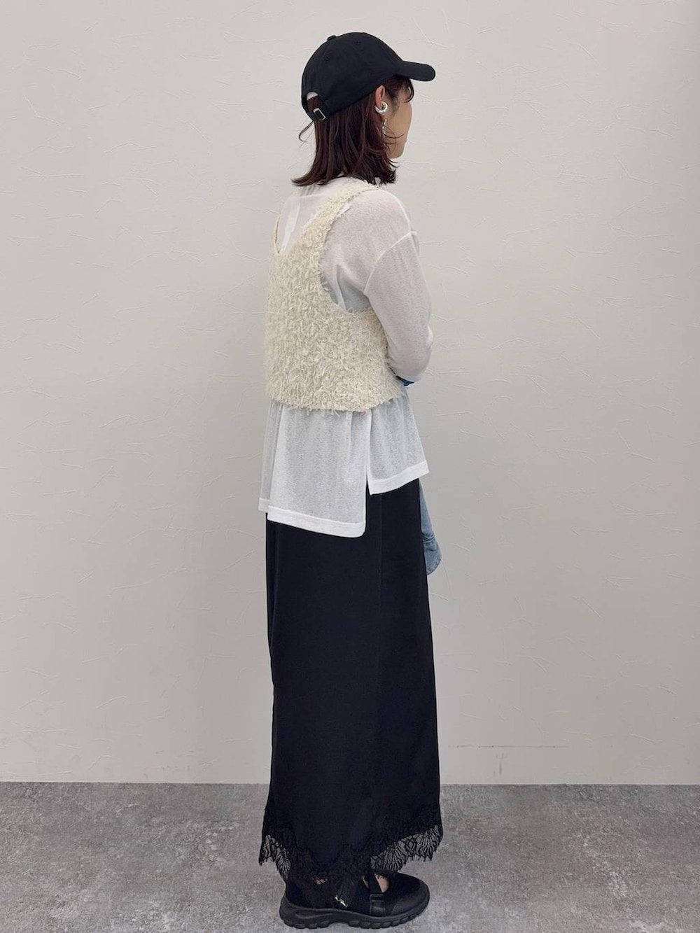 ブラック系のスニーカー、ホワイト系のベスト、シルバー系のネックレスを着用したレディースの春コーディネートの6枚目の写真