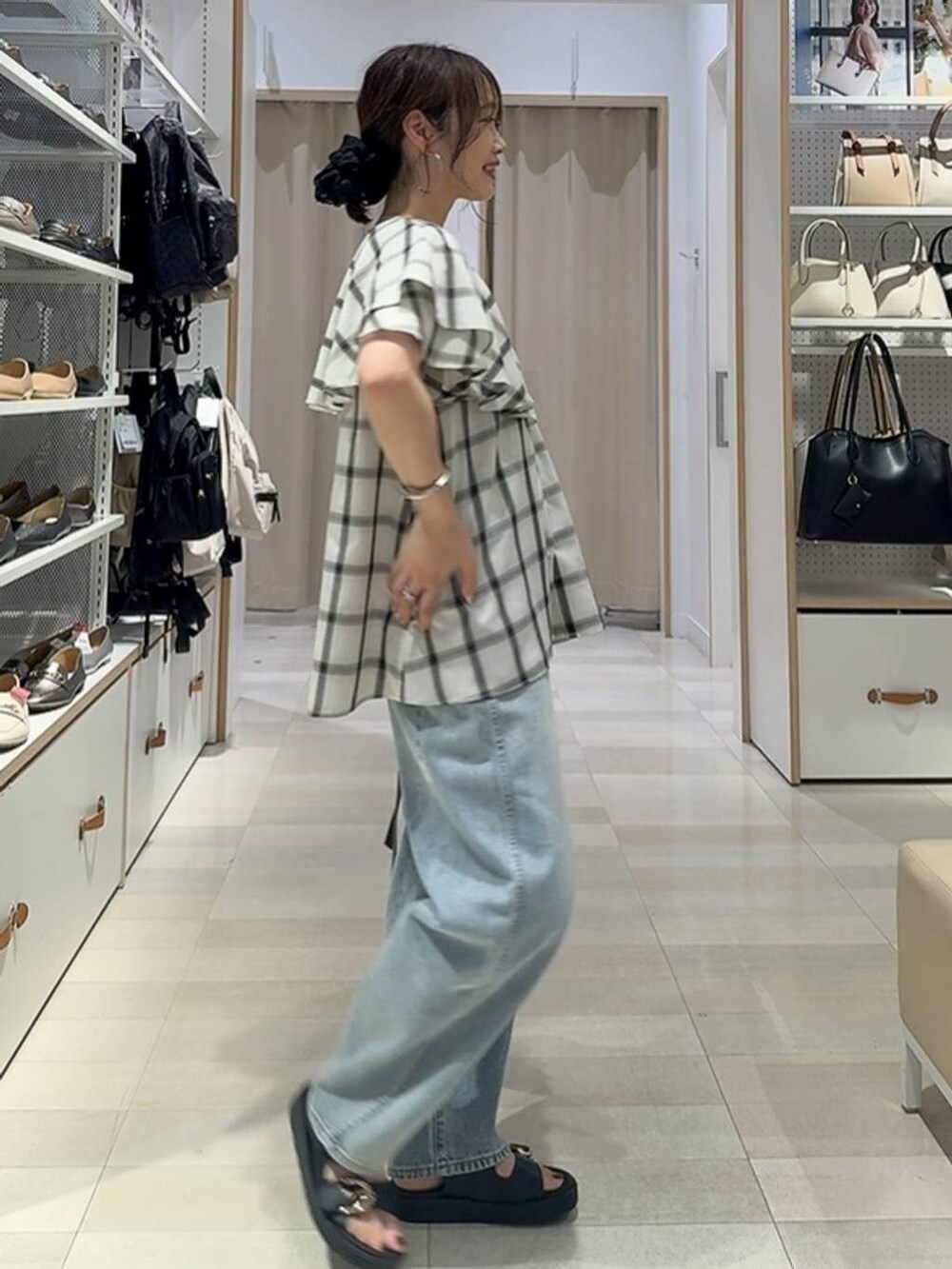 ブルー系のデニムパンツ、ブラウン系のショルダーバッグ、ホワイト系のシャツ/ブラウスを着用したレディースの夏コーディネートの2枚目の写真