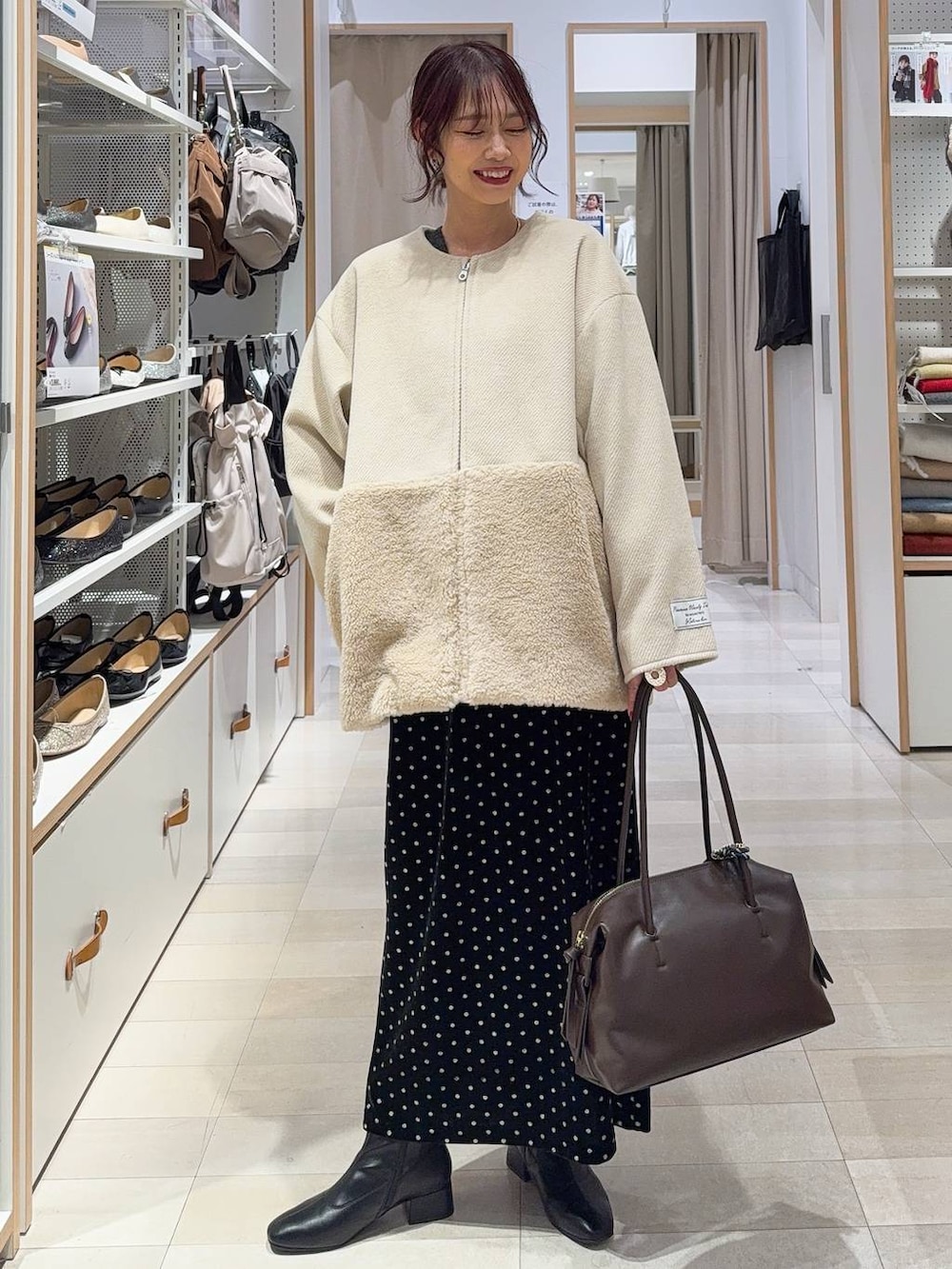 ブラウン系のボストンバッグ、ホワイト系のTシャツ/カットソー、ブラック系のスカートを着用したレディースの秋コーディネートの3枚目の写真