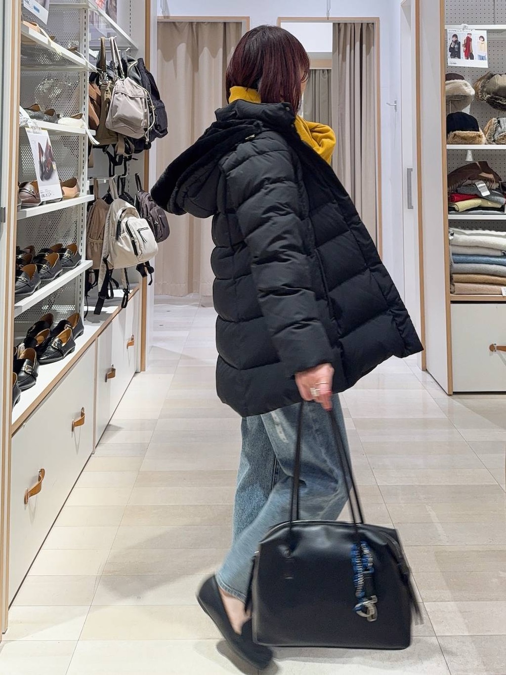 ブラック系のボストンバッグ、ブラック系のダウンジャケット/コート、ブルー系のデニムパンツを着用したレディースの秋コーディネートの5枚目の写真