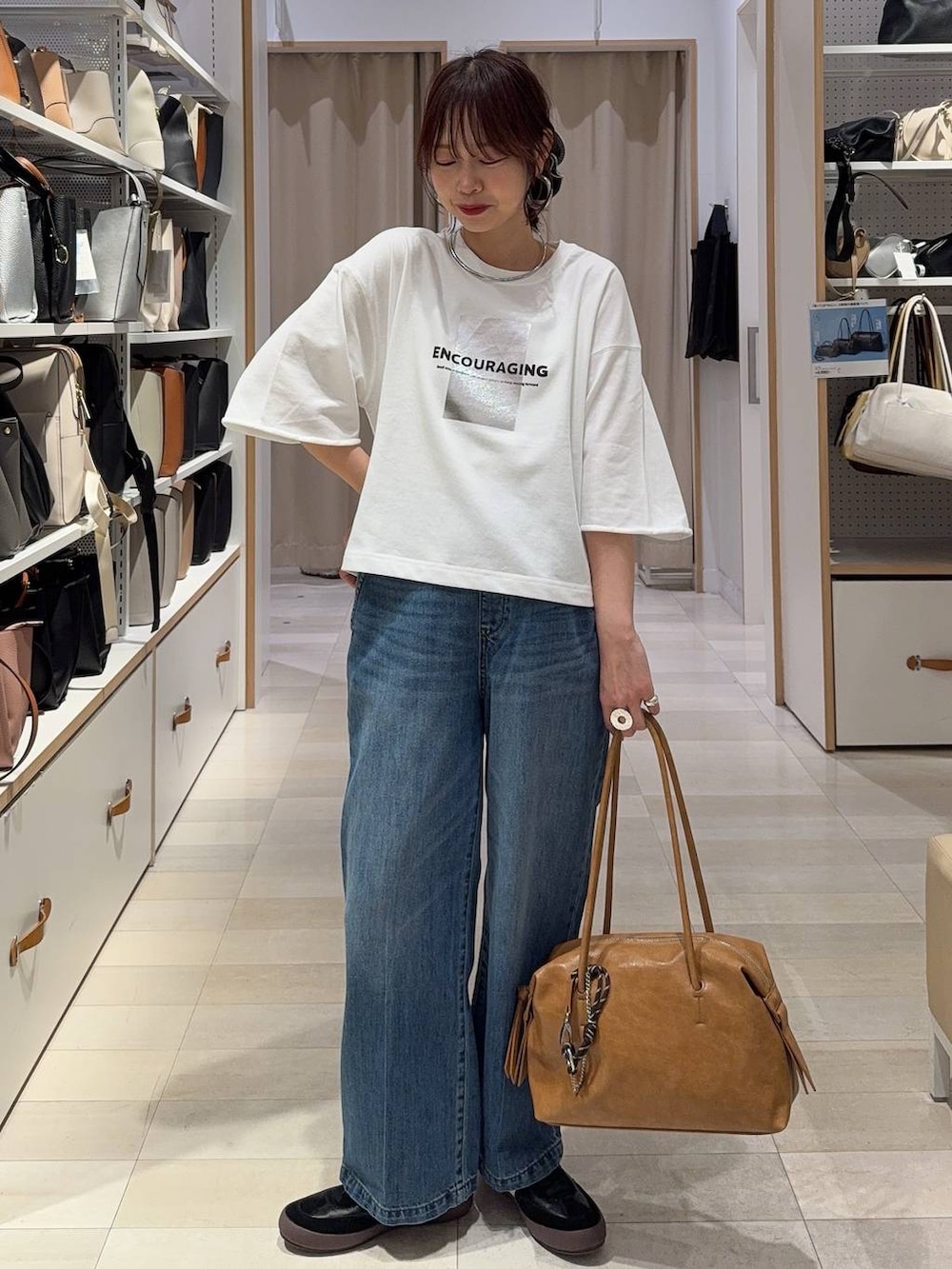 ブラック系のスニーカー、ブルー系のデニムパンツ、ベージュ系のパーカーを着用したレディースの春コーディネートの3枚目の写真