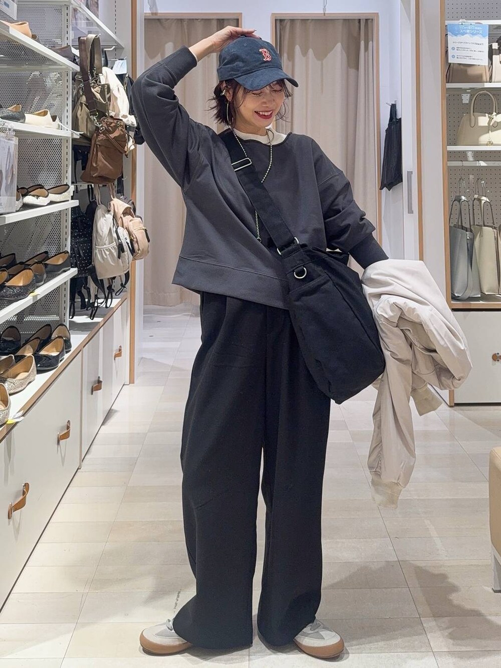 グレー系のスニーカー、ブラック系のショルダーバッグ、ベージュ系のブルゾンを着用したレディースの秋コーディネートの2枚目の写真