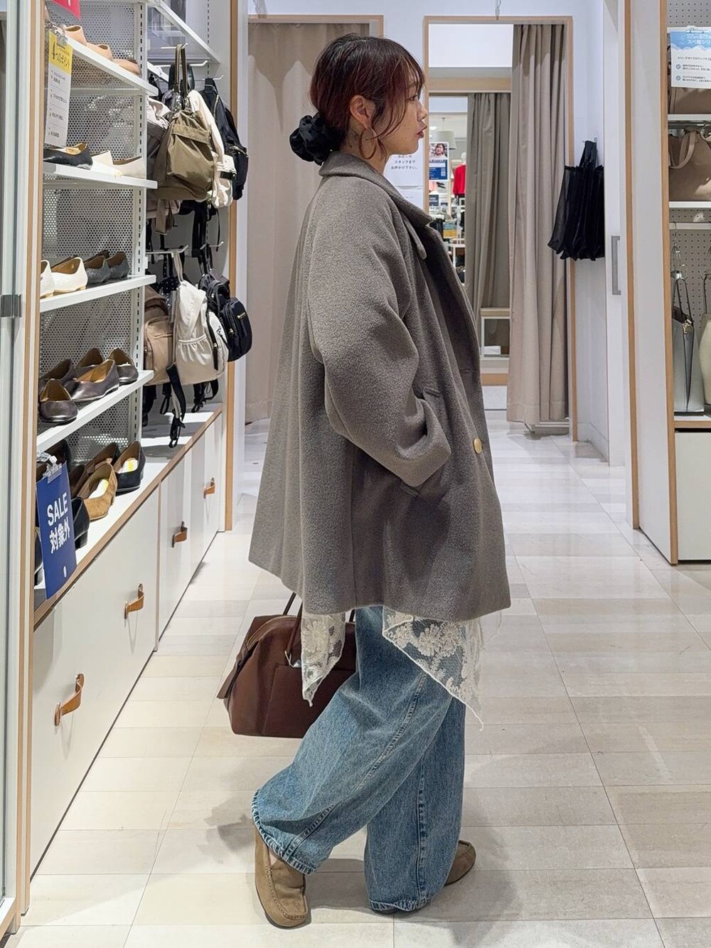 ブラウン系のボストンバッグ、ブルー系のデニムパンツ、ブラウン系のチェスターコートを着用したレディースの秋コーディネートの5枚目の写真