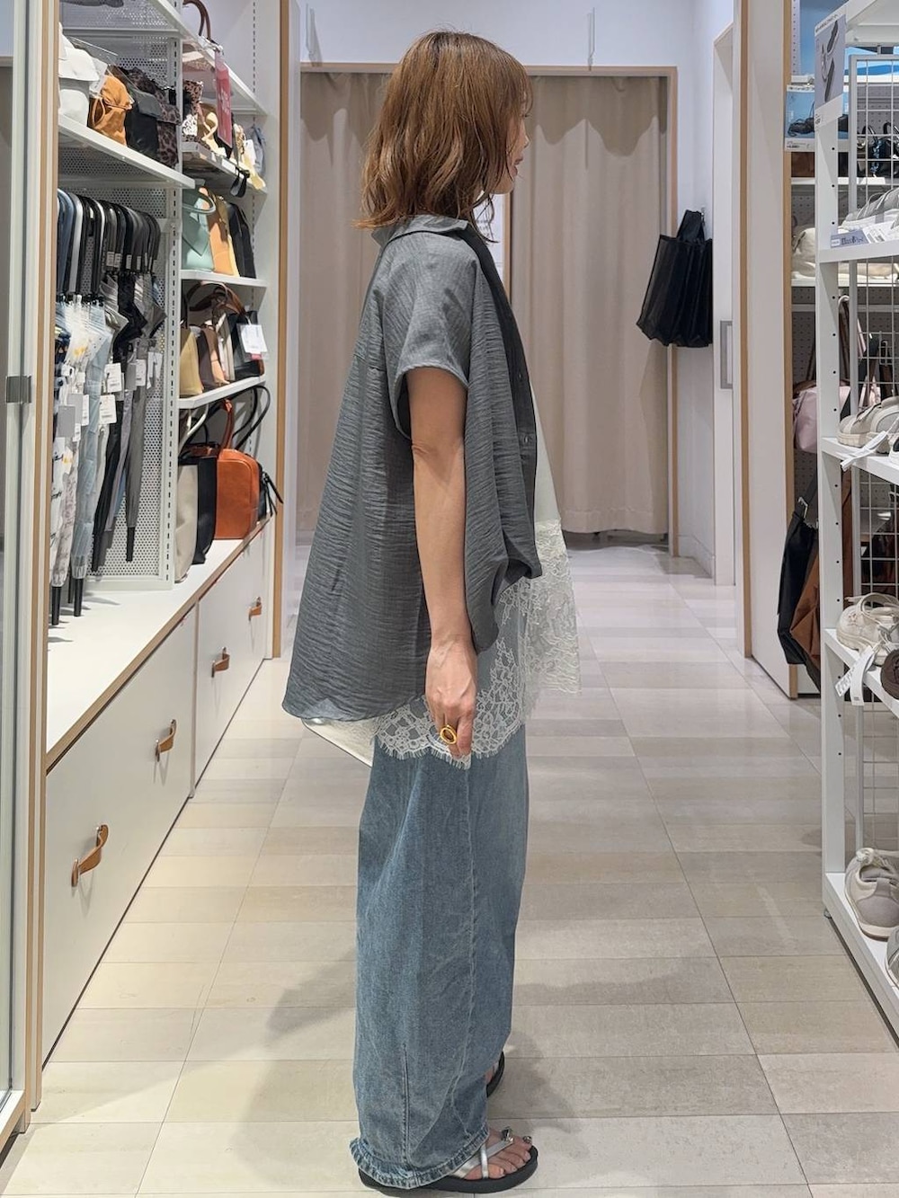 シルバー系のショルダーバッグ、ブルー系のデニムパンツ、ホワイト系のキャミソールを着用したレディースの夏コーディネートの3枚目の写真