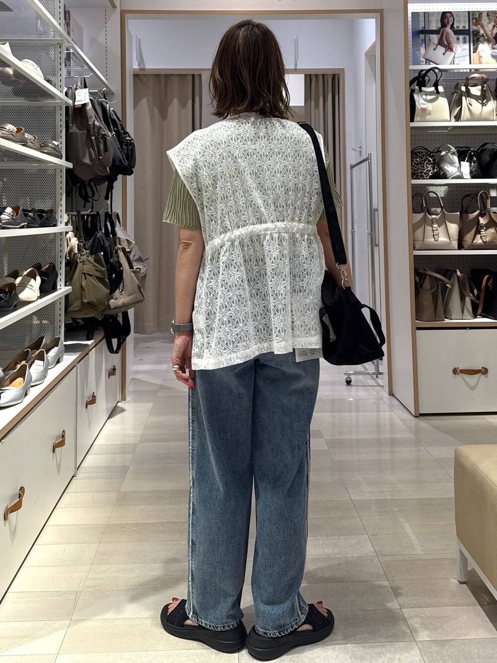ブルー系のデニムパンツ、ブラック系のトートバッグ、グリーン系のTシャツ/カットソーを着用したレディースの春コーディネートの5枚目の写真