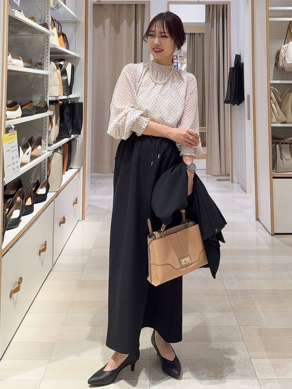 ブラック系のパンプス、ブラック系のノーカラージャケット、ベージュ系のショルダーバッグを着用したレディースの冬コーディネートの2枚目の写真