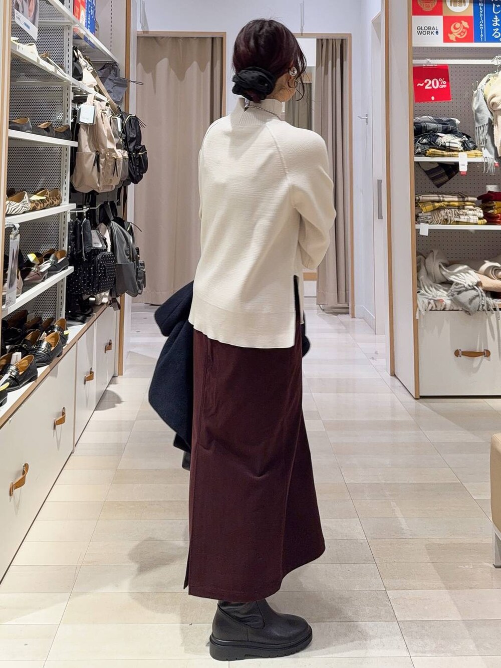 ブラック系のボストンバッグ、ブルー系のチェスターコート、レッド系のスカートを着用したレディースの冬コーディネートの6枚目の写真