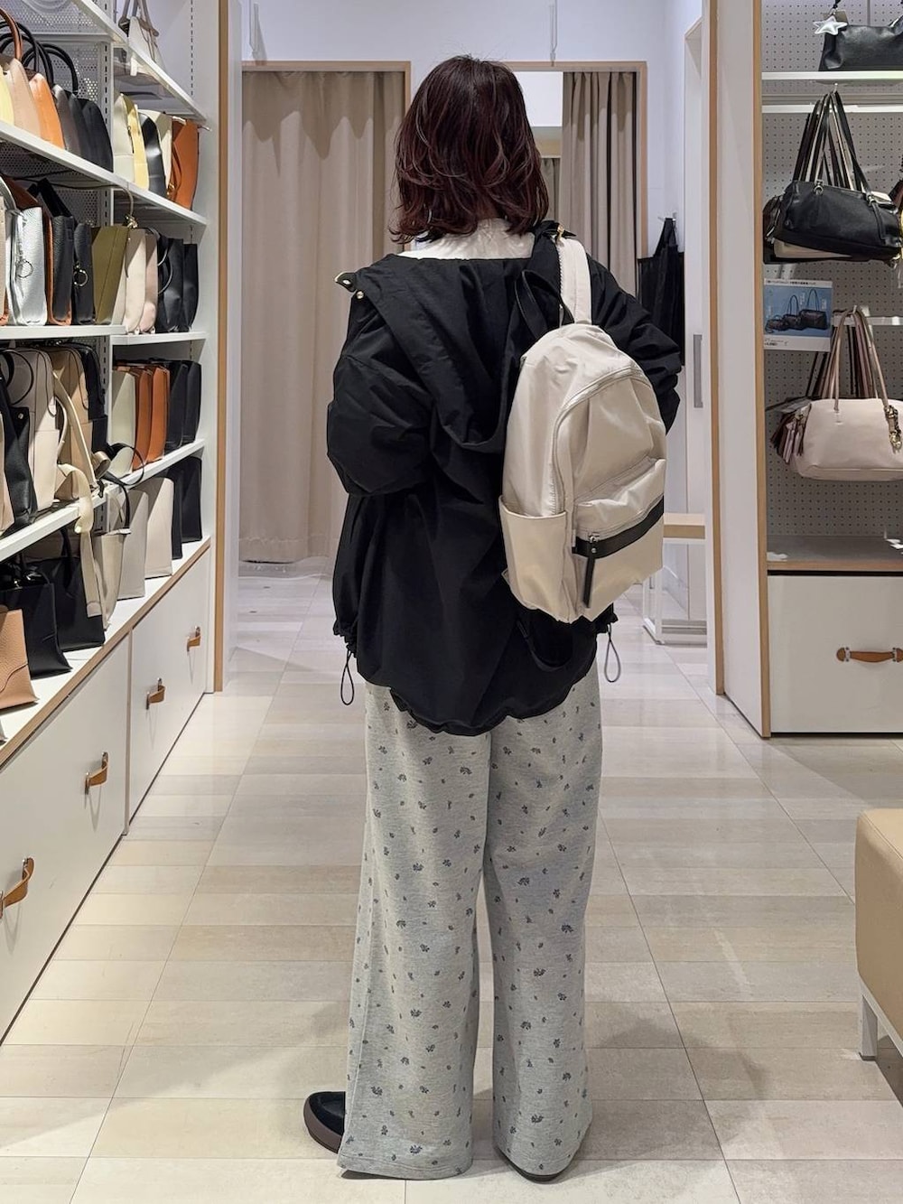 ブラック系のスニーカー、ホワイト系のバックパック/リュック、ブラック系のマウンテンパーカーを着用したレディースの春コーディネートの4枚目の写真