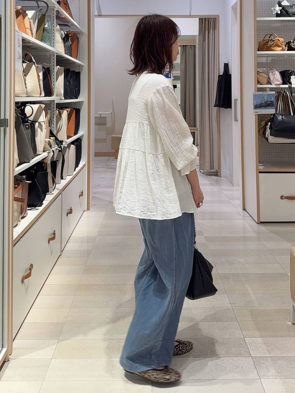 ブラウン系のベスト、ブルー系のデニムパンツ、その他のネックレスを着用したレディースの春コーディネートの8枚目の写真