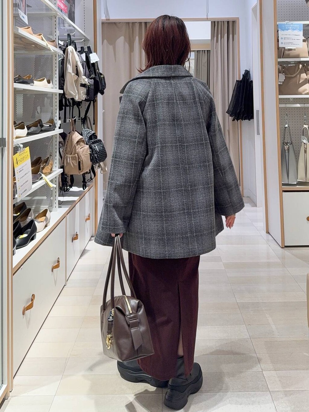 ブラウン系のボストンバッグ、グレー系のチェスターコート、レッド系のスカートを着用したレディースの秋コーディネートの5枚目の写真