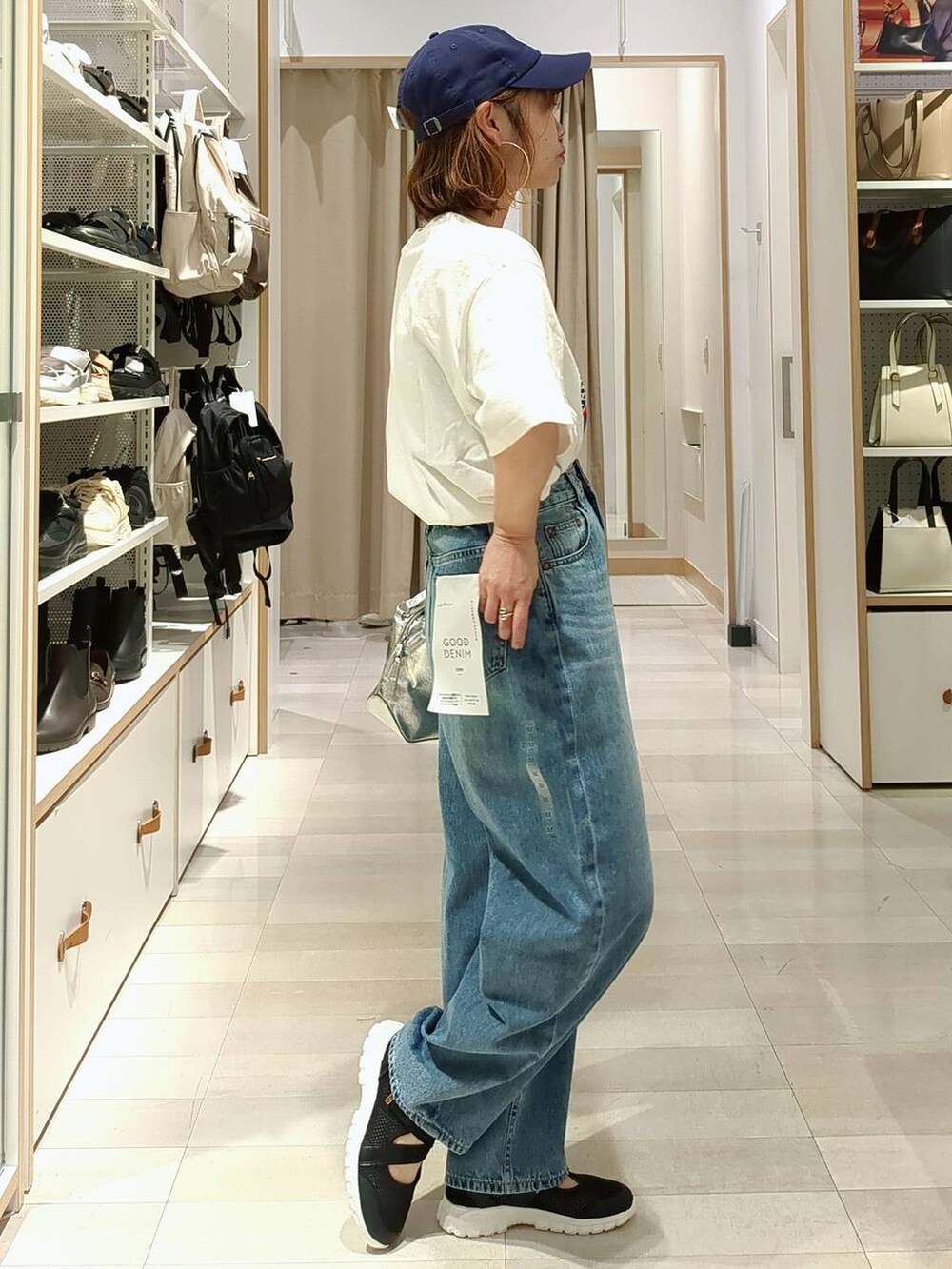 ブラック系のスニーカー、シルバー系のショルダーバッグ、ブルー系のデニムパンツを着用したレディースの春コーディネートの6枚目の写真