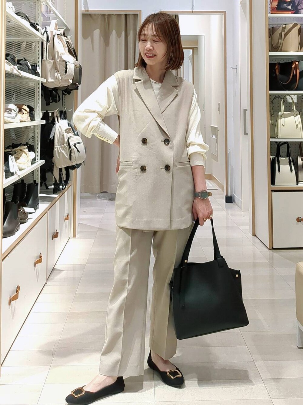 ブルー系のその他パンツ、ベージュ系のベスト、ブラック系のショルダーバッグを着用したレディースの春コーディネートの2枚目の写真