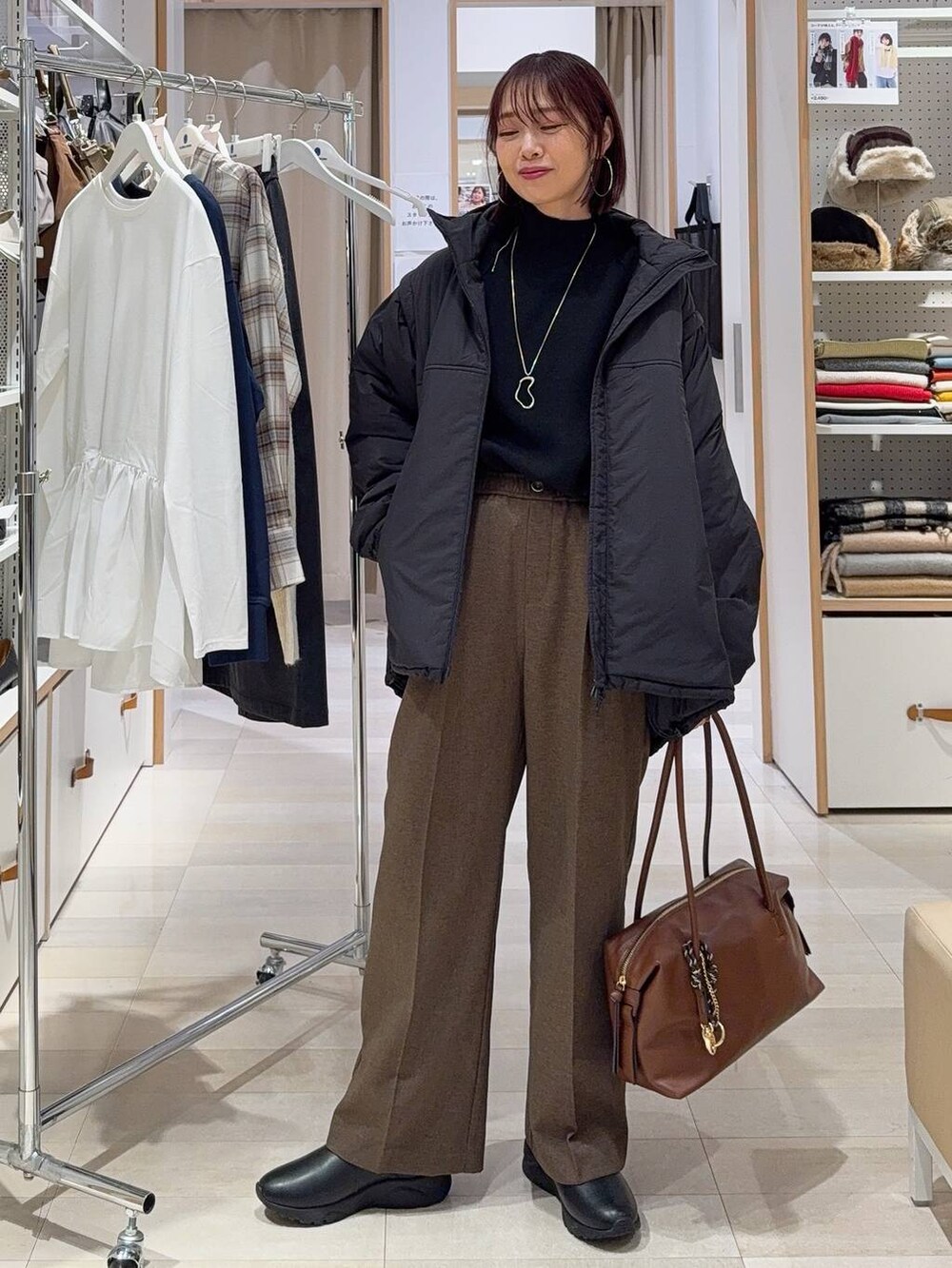 ブラック系のブルゾン、ブラウン系のボストンバッグ、ブラック系のブーツを着用したレディースの秋コーディネートの2枚目の写真