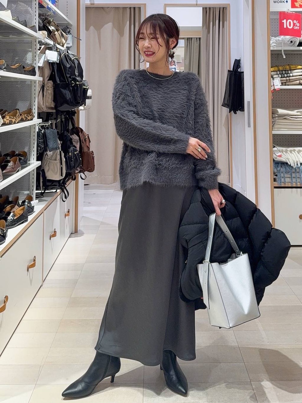 シルバー系のショルダーバッグ、ベージュ系のダウンジャケット/コート、グレー系のニット/セーターを着用したレディースの冬コーディネートの2枚目の写真