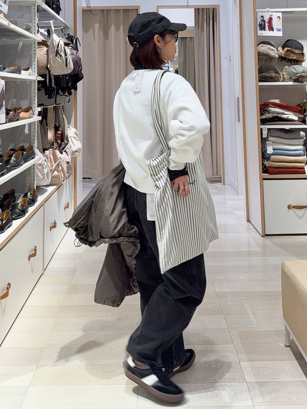 ブラック系のスニーカー、ブラウン系のダウンジャケット/コート、ブラック系のデニムパンツを着用したレディースの秋コーディネートの7枚目の写真